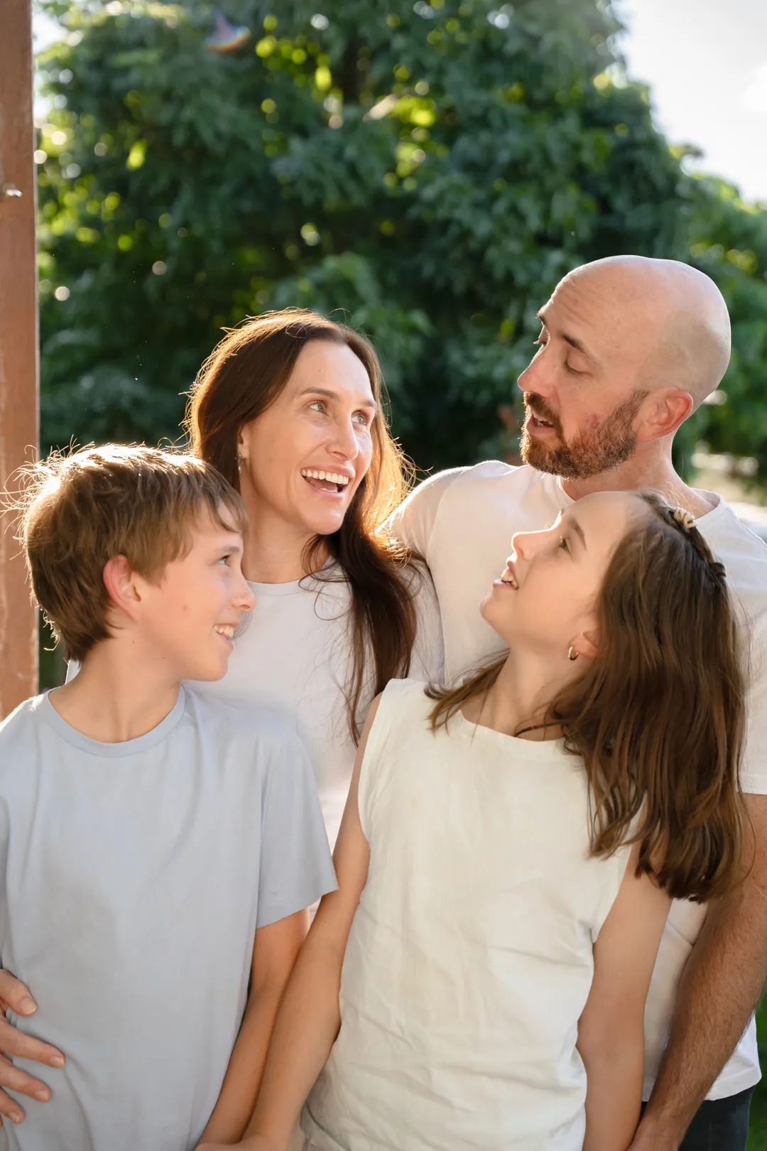 A family of four laughing together outdoors at golden hour